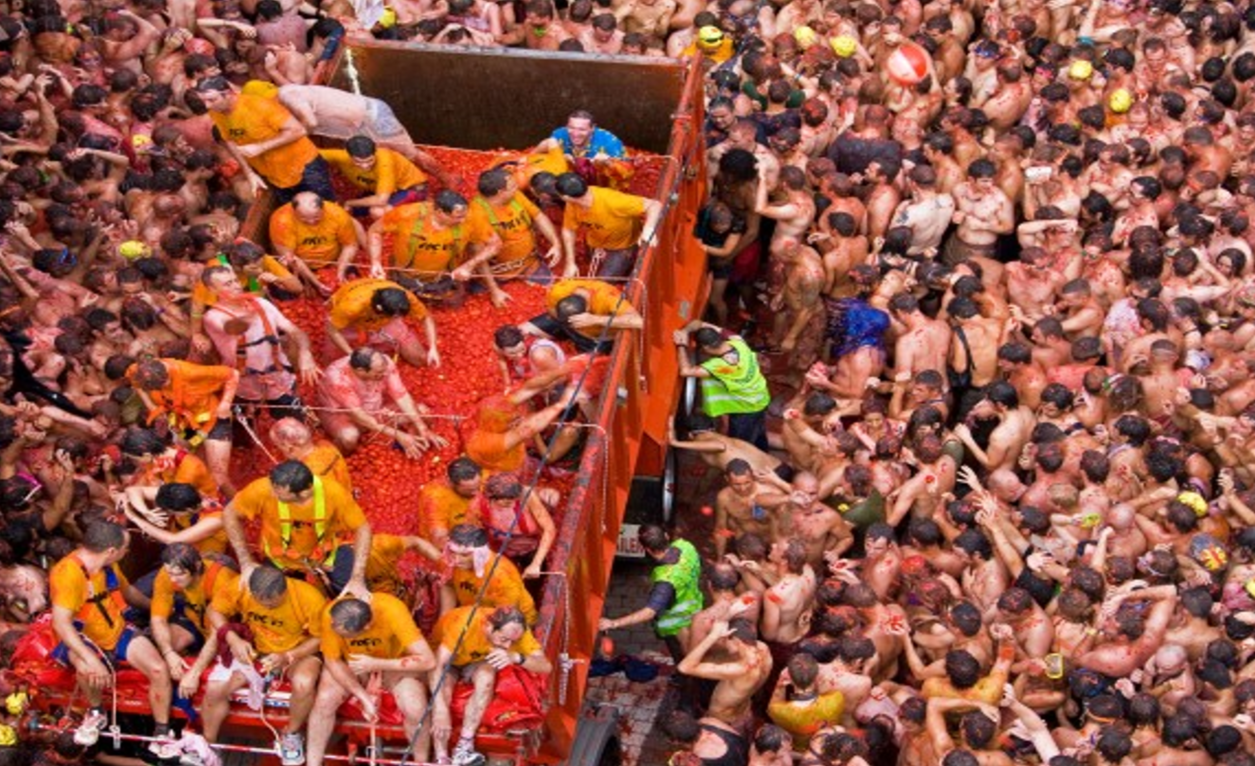 토마토를 가득 실은 트럭과 축제를 즐기는 사람들